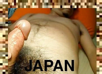 A Japanese guy jerks off his erected dick and cums playing with his nipples