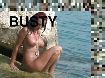 Busty Brunette Was Posing Naked On The Rocks By The Sea