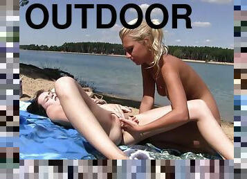 Outdoor fun by the beach between two naked lesbians