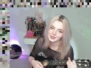 Hot blonde girl playing on ukulele and singing in naughty outfit