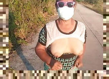 Auntie walks and shows off her breasts on the side of the road.